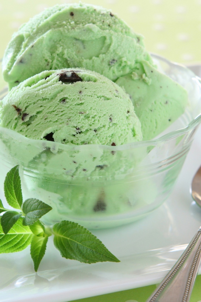 Зеленые шарики мороженого с шоколадом и мятой на тарелке с ложкой