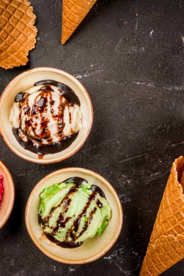 Шарики мороженого с вафельными рожками на столе 