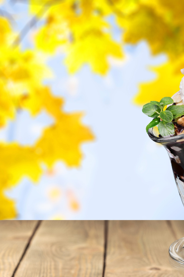 Мороженое в креманке с вишенкой на фоне желтых листьев