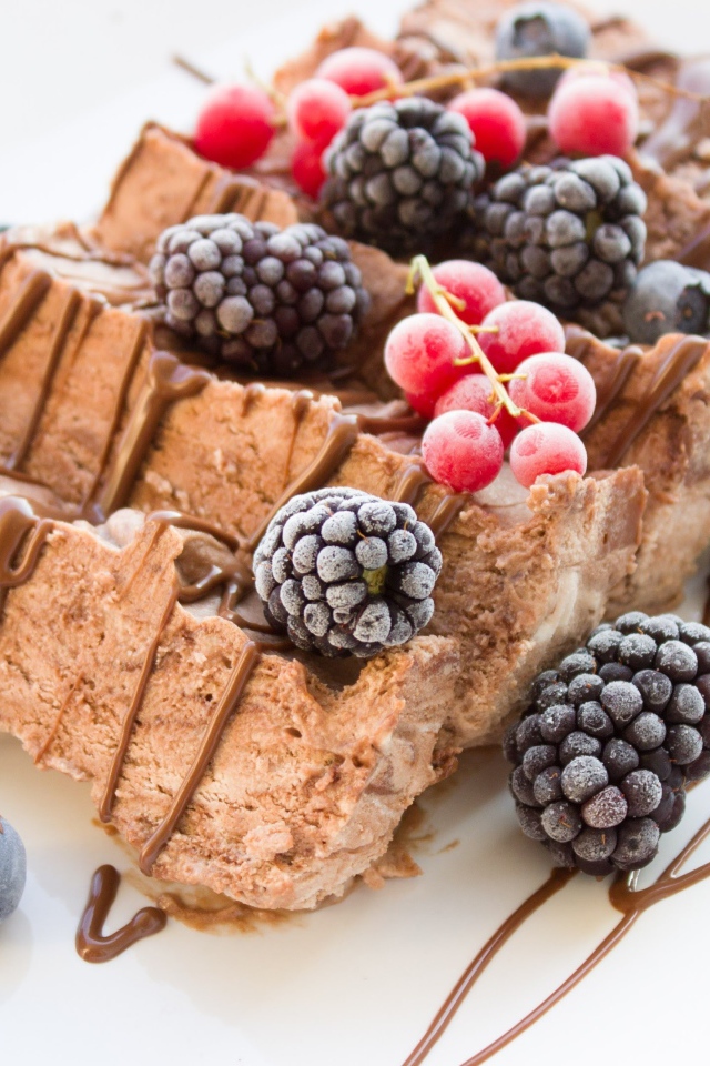 Мороженое с ягодами ежевики и красной смородины на белой тарелке 