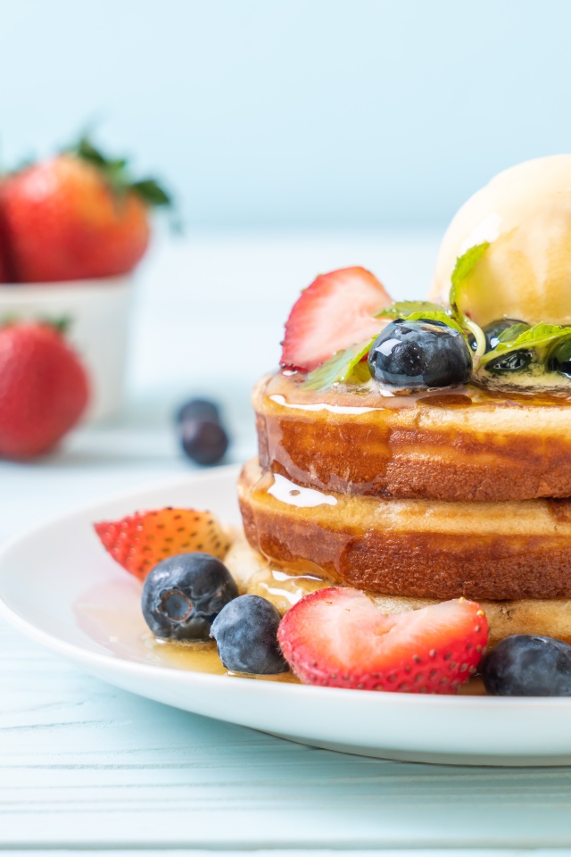 Оладья и медом, мороженым и ягодами черники и клубники на столе