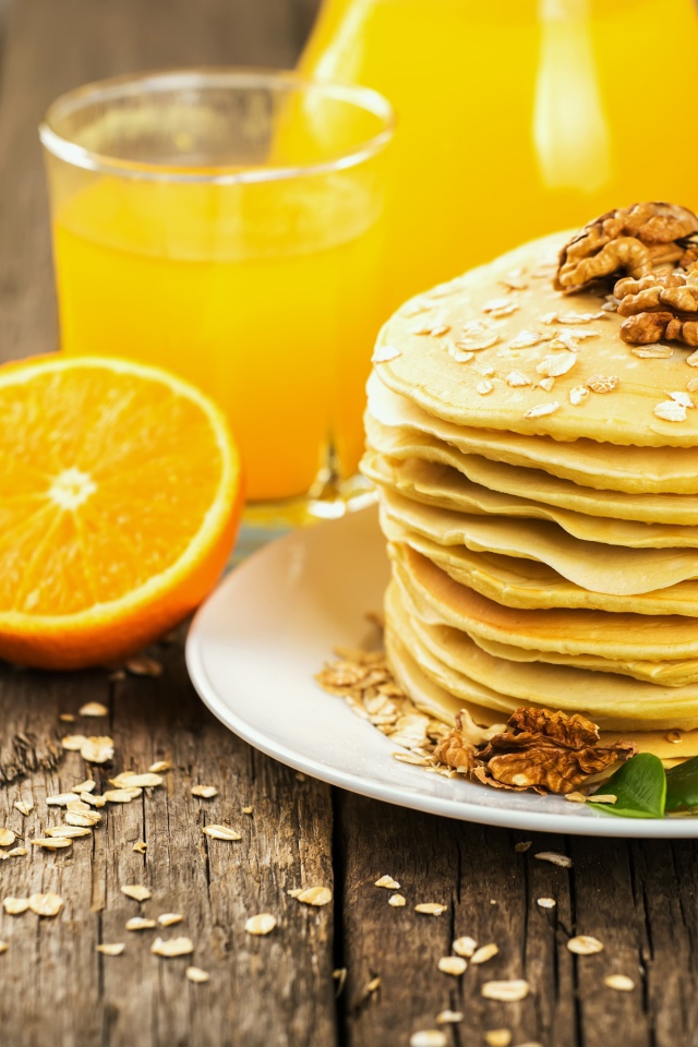 Оладьи с орехами на столе с апельсиновым соком и апельсинами