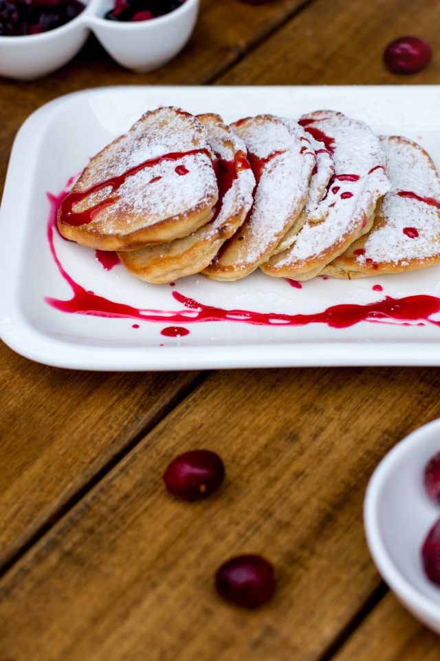 Оладьи с сахарной пудрой и вареньем на белой тарелке
