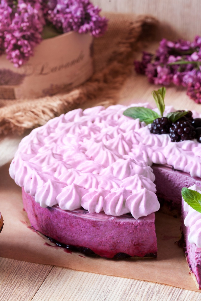 Пирог с кремом и вкусными кексами с черникой на столе с цветами сирени