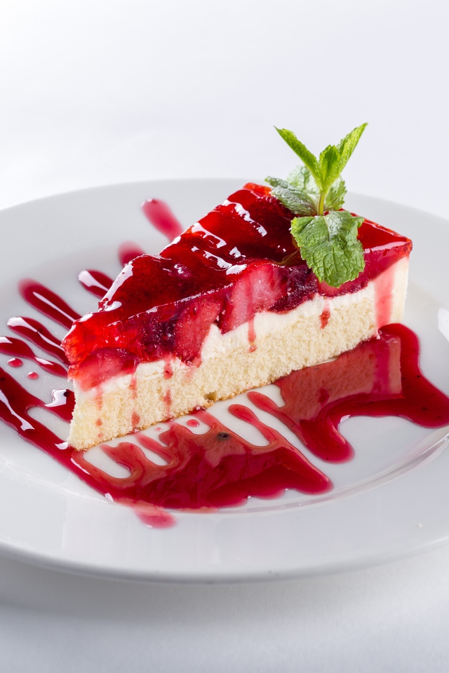 Кусок пирога с клубникой и джемом на белой тарелке