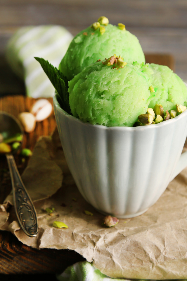 Фисташковое мороженое в белой чашке на столе