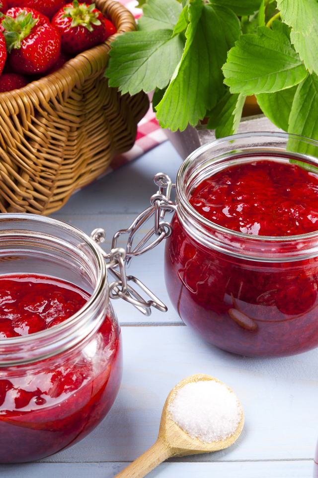 Клубничное варенье в стеклянных баночках на столе  ягодами
