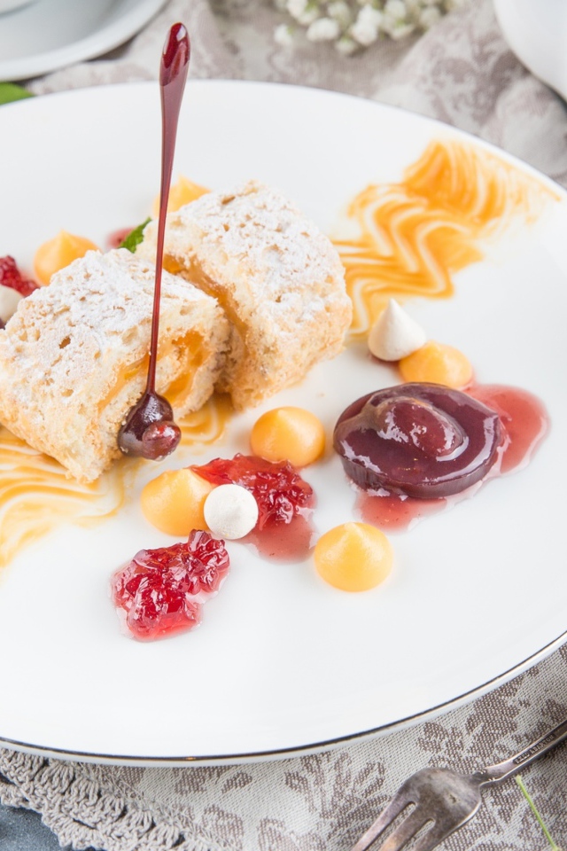 Сладкий рулет с сухофруктами и джемом на тарелке 