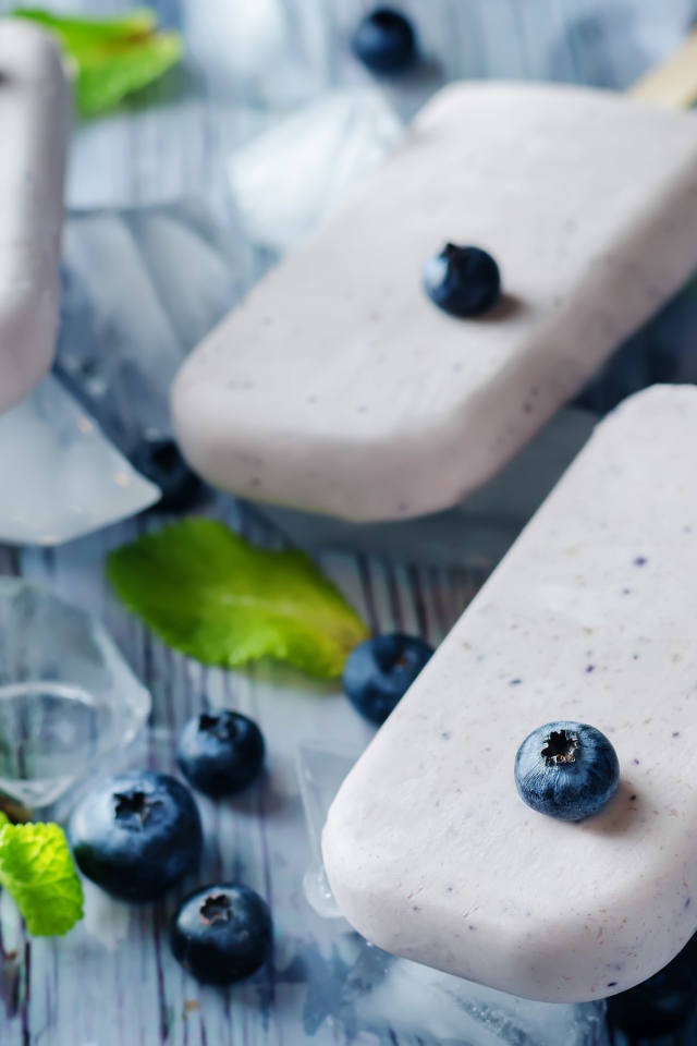 Вкусное мороженое с ягодами черники на столе с кусочками льда