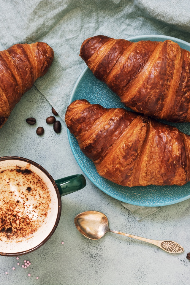 Три круассана на столе с чашкой кофе