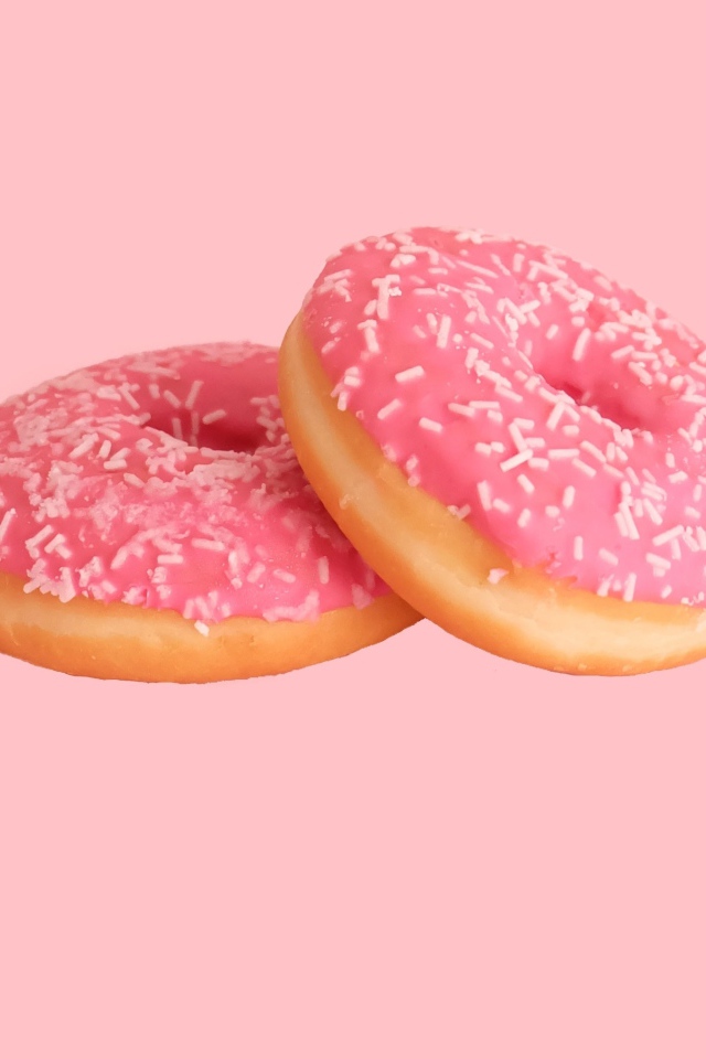 Два пончика с глазурью на розовом фоне