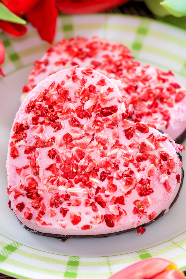 Два печенья в форме сердца на тарелке с тюльпанами 