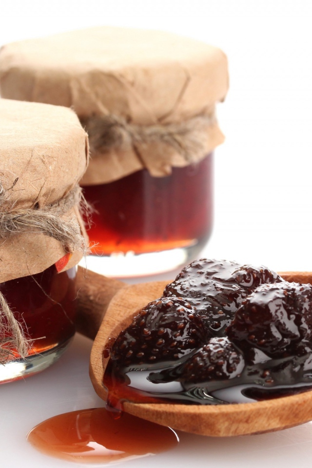 Две банки клубничного варенья на столе с ложкой 