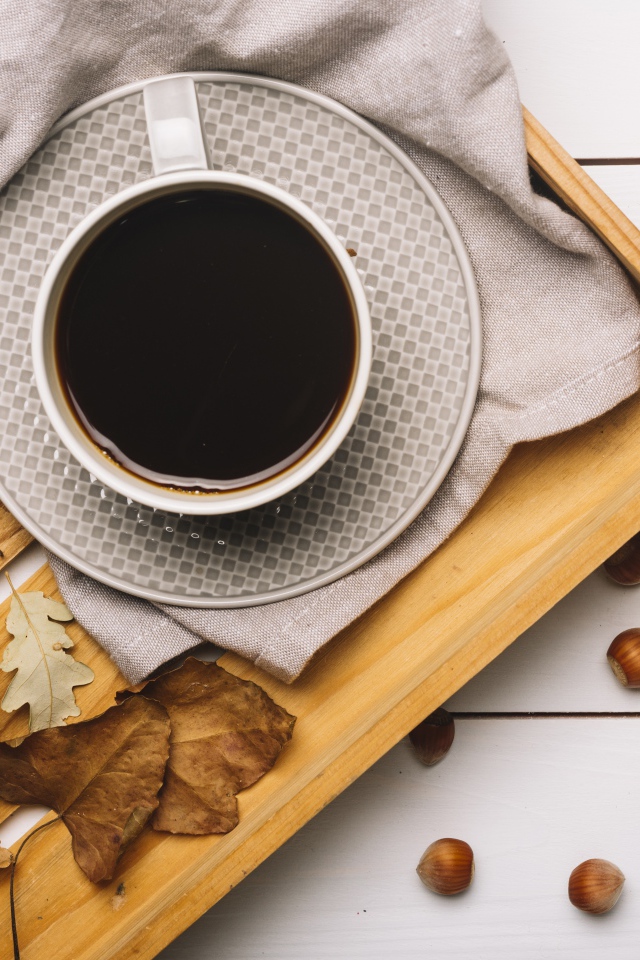 Чашка кофе на столе с лесными орехами и желтыми листьями