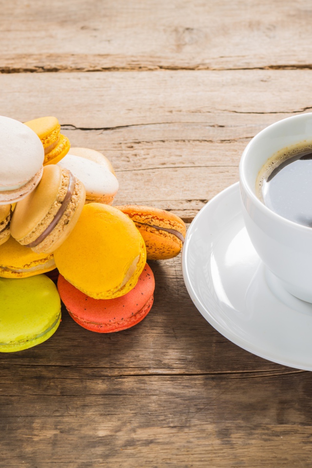 Чашка кофе на столе с разноцветными макарунами