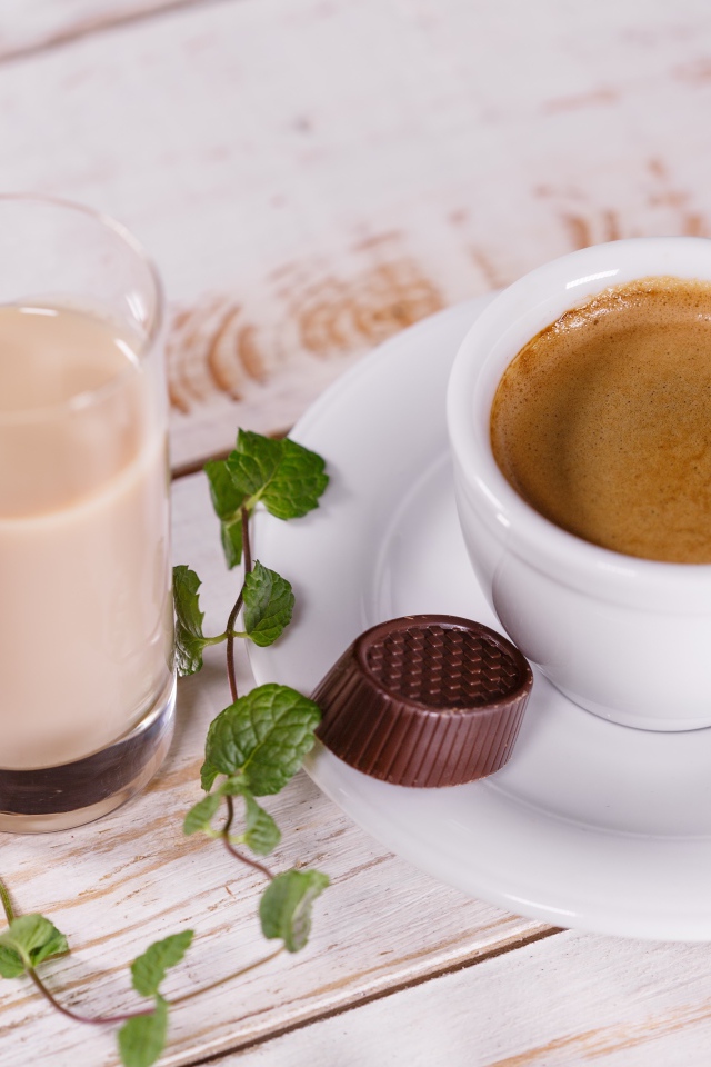 Чашка кофе с шоколадной конфетой и стаканом молока на столе