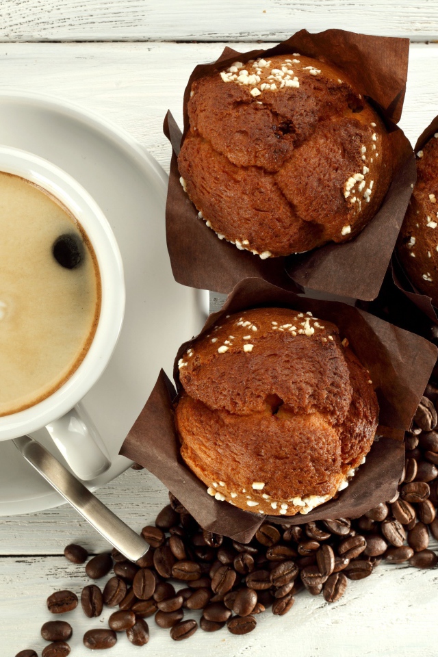 Чашка кофе с кексами и кофейными зернами на столе