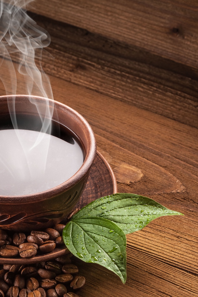 Чашка горячего кофе с зернами на деревянном столе