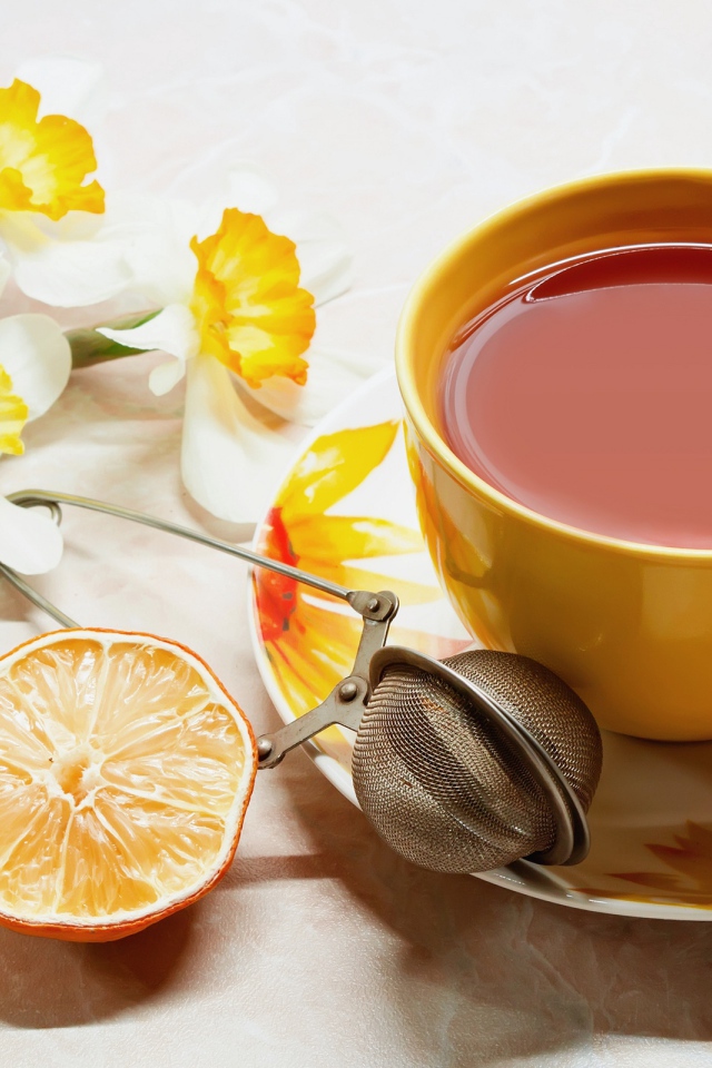 Чашка чаю на столе с лимоном и цветами нарцисса 