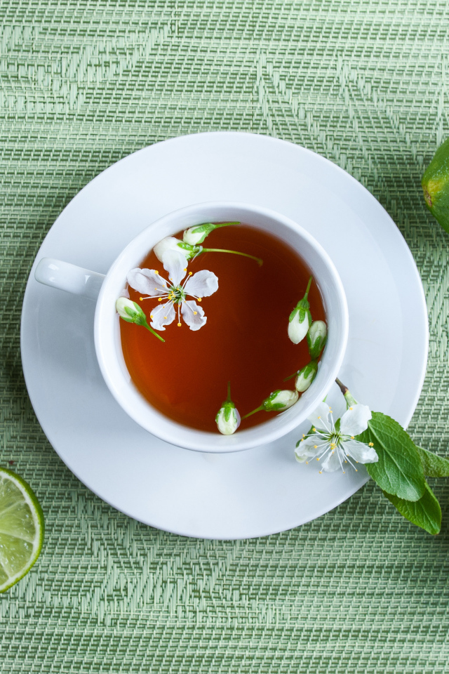 Чашка чая с зелеными лаймами на столе
