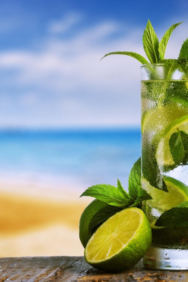 Стакан холодного мохито на столе с мятой и лаймом