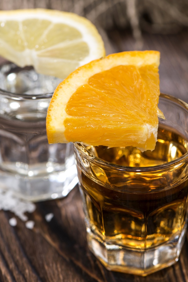 Рюмка водки и рюмка виски на столе с кусочками лимона