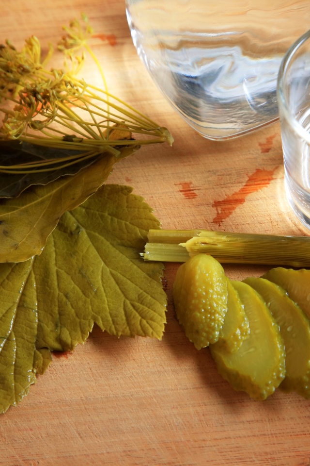 Рюмка водки на столе с соленым огурцом