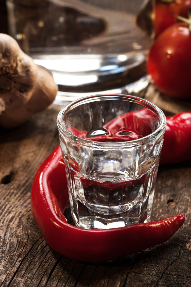 Рюмка водки на столе с красным перцем и чесноком