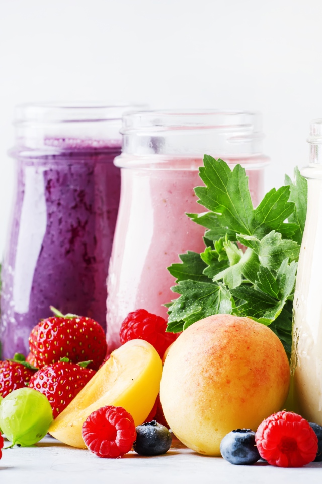 Ягодные смузи в бутылочках на столе с ягодами