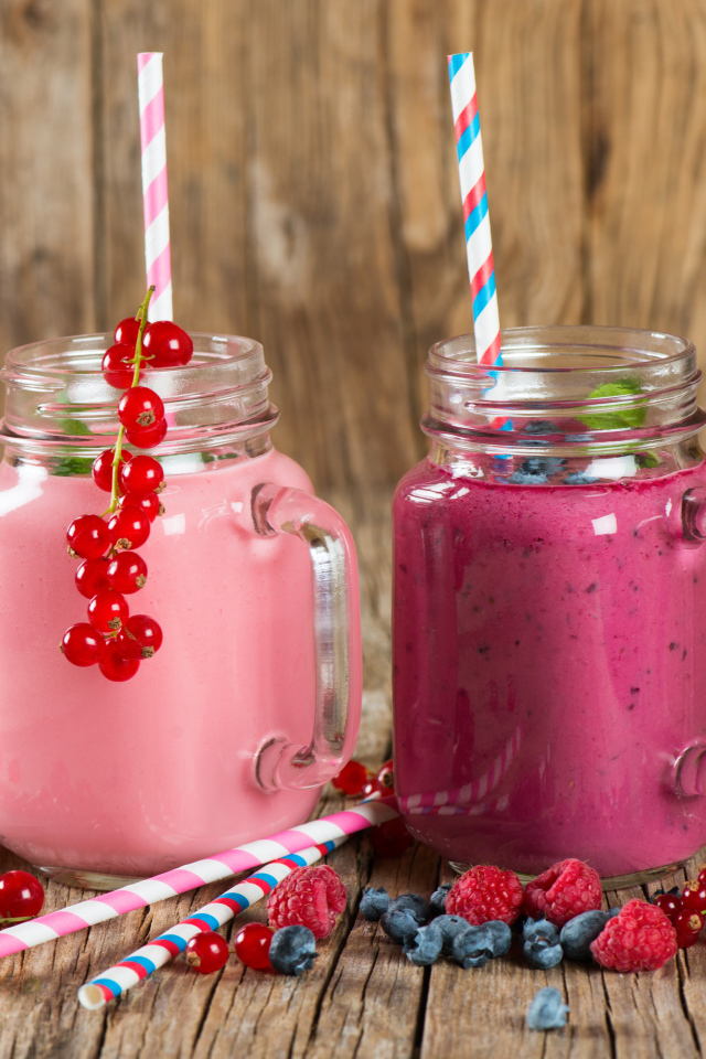 Ягодное смузи в баночках на столе со свежими ягодами малины, смородины и черники