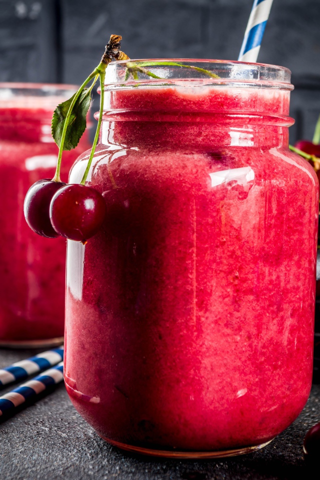 Вишневое смузи в стеклянной банке на столе с ягодами