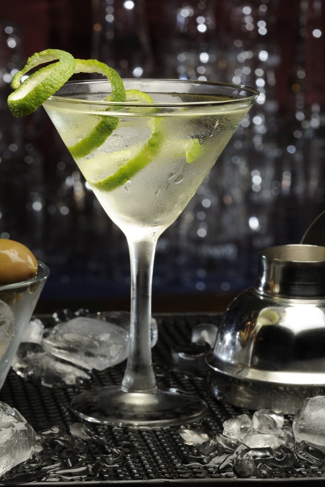Коктейль с лаймом на столе с оливками и кубиками льда