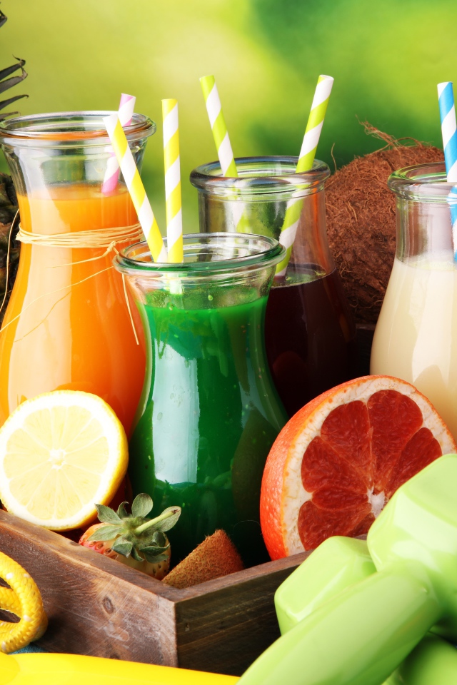 Коктейли в бутылках с трубочками на столе фруктами