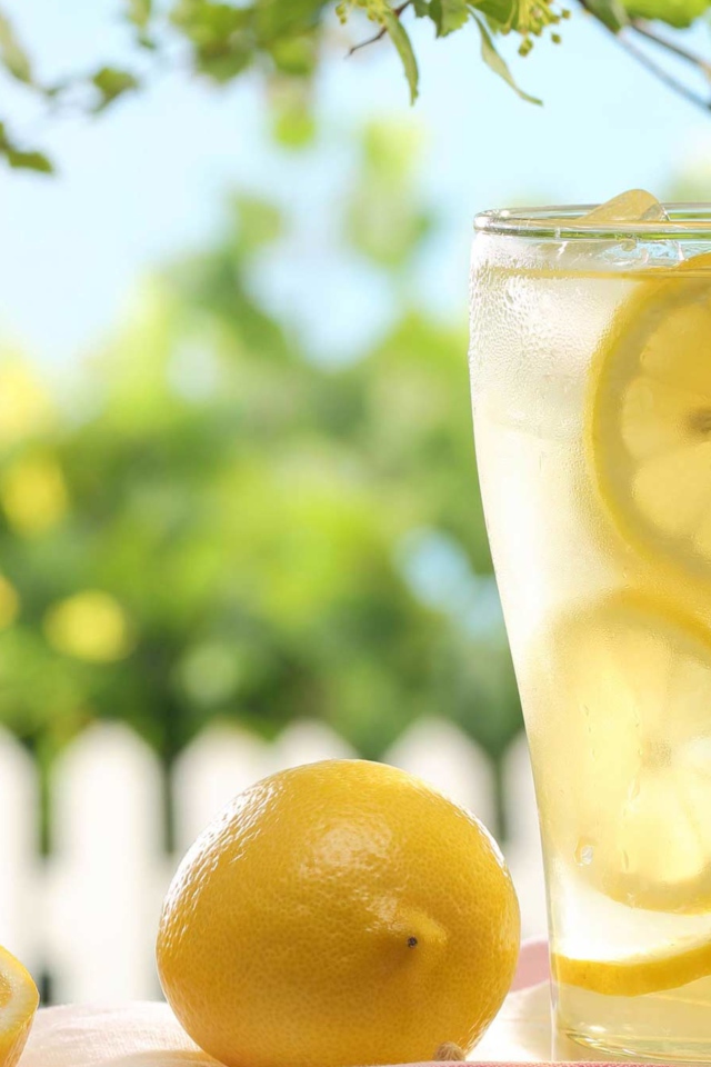 Холодный лимонад в стакане с кусочками лимона