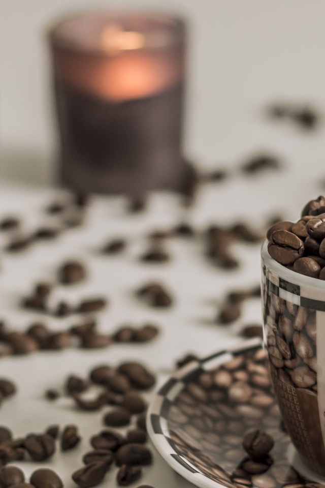 Чашка с кофейными зернами на столе со свечами