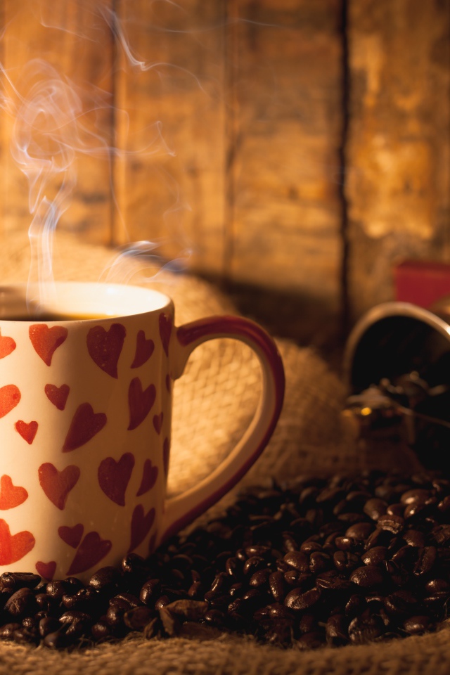 Чашка с горячим кофе на столе с кофейными зернами и корицей