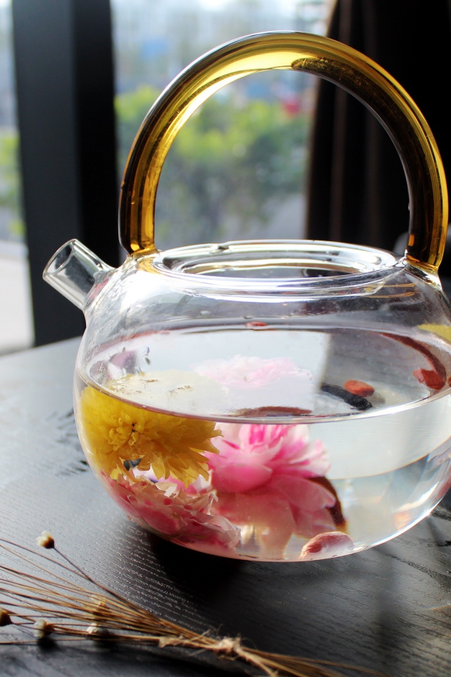 Цветочный чай в стеклянном чайнике на столе 