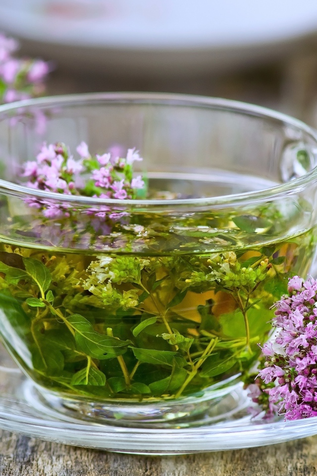 Стеклянная чашка зеленого чая с цветами чабреца