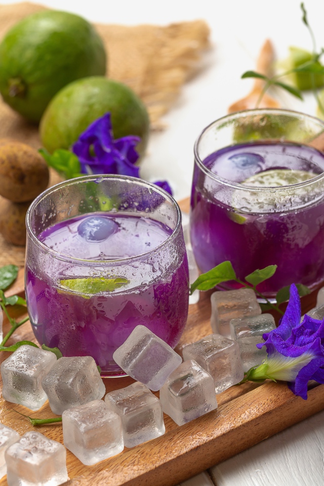 Стаканы с напитком на столе с лаймом и кубиками льда