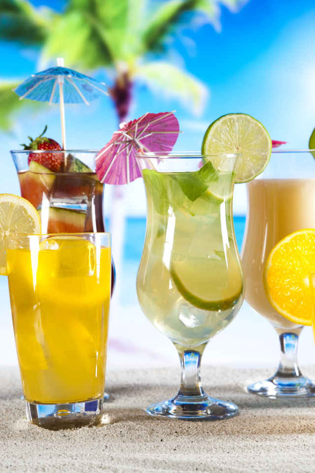 Бокалы с тропическими коктейлями на песке на пляже