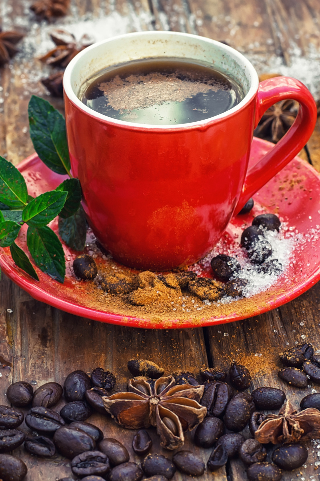 Красная чашка кофе на столе с зернами  и бадьяном и корицей