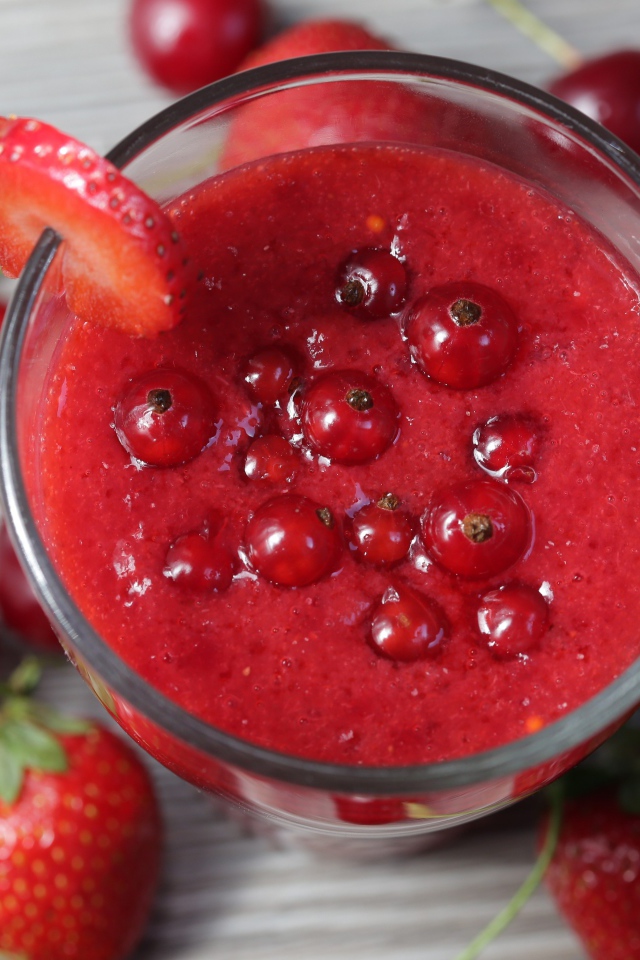 Смузи в стакане с ягодами клубники, красной смородины и вишни