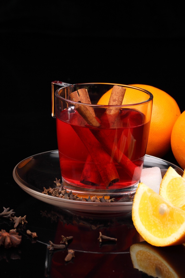 Чай с корицей и кусочками апельсина на черном фоне