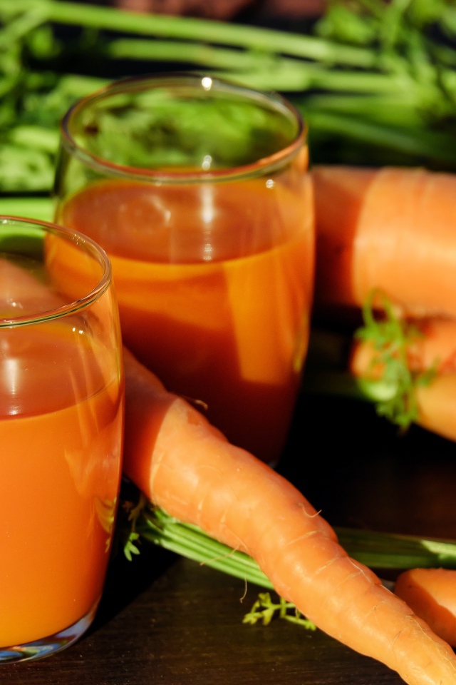 Два стакана морковного сока на столе со свежей морковью 