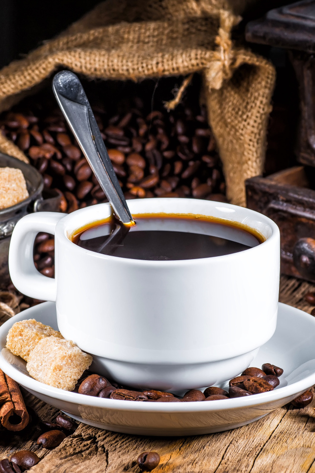 Белая чашка кофе на столе с сахаром, корицей и бадьяном 