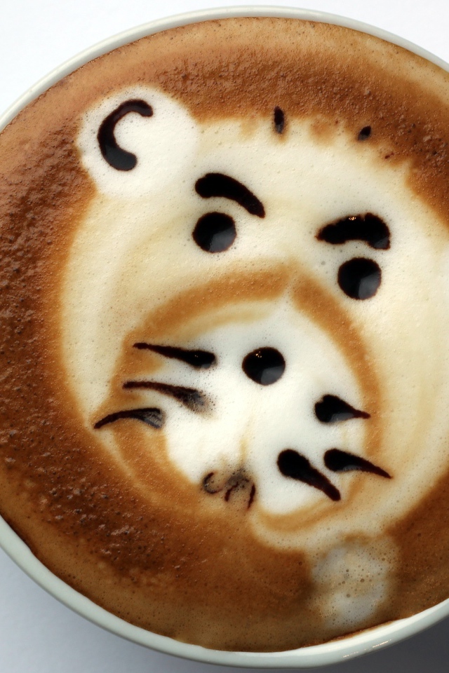 Белая чашка кофе с забавным рисунком на пене