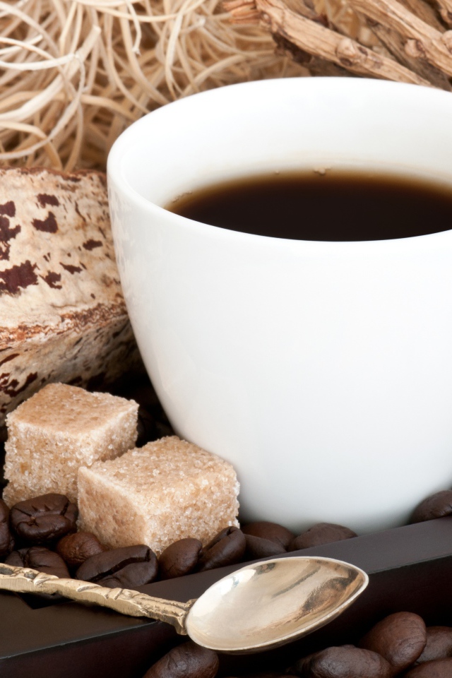 Белая чашка кофе с зернами и кусочками сахара на столе 