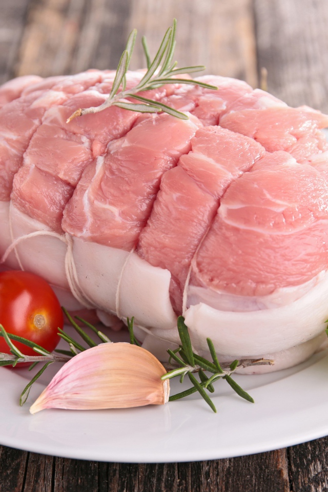 Кусок свежего мяса со свежими помидорами, чесноком и листьями салата