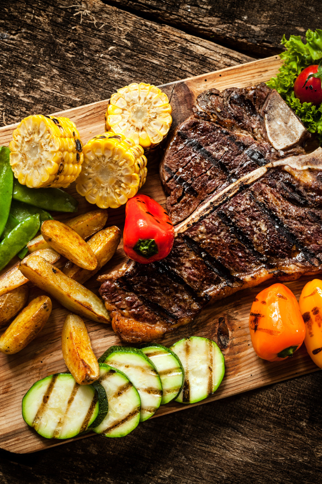 Кусок мяса на разделочной доске с овощами