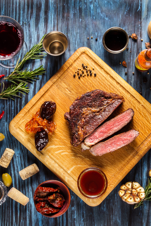 Кусок мяса на столе со специями и стаканом вина